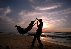 Father swings his child in the air, celebrating work-life balance.